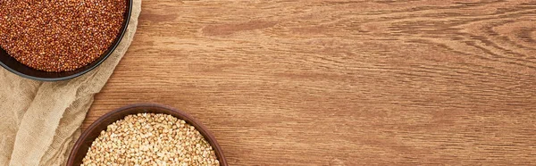 Panoramic shot of bowls with diverse buckwheat on wooden surface with canvas — Stock Photo