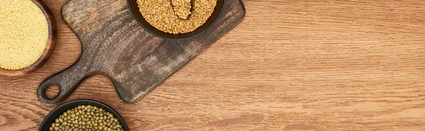 Panoramic shot of bowls with couscous and beans on wooden cutting board — Stock Photo