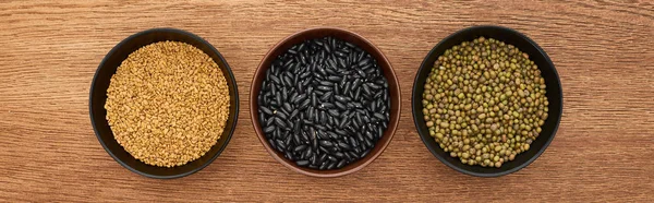 Panoramic shot of bowls with diverse beans on wooden surface — Stock Photo