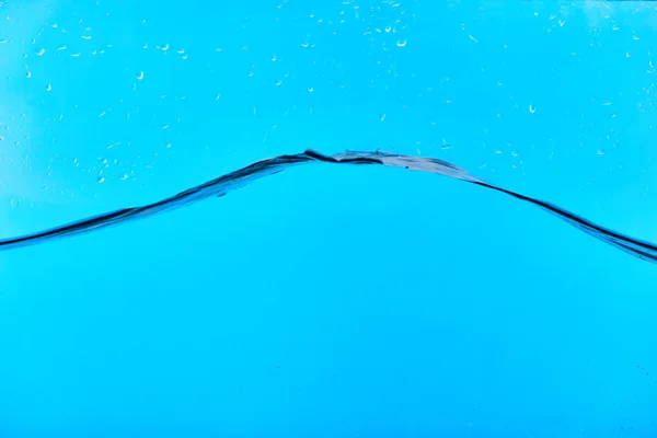 Eau douce claire ondulée sur fond bleu avec des gouttes — Photo de stock