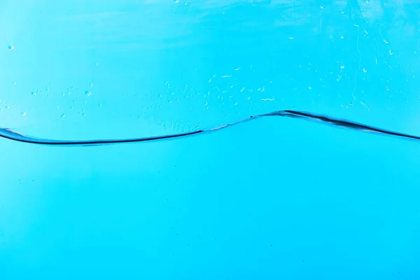 Волнистая чистая вода на голубом фоне с капельками — стоковое фото