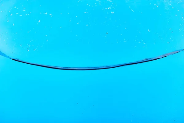 Eau douce claire ondulée sur fond bleu avec des gouttelettes — Photo de stock