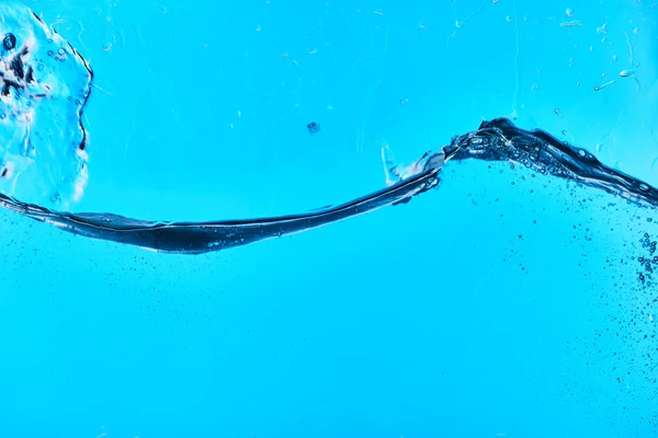Welliges klares Spritzwasser auf blauem Hintergrund mit Tropfen — Stockfoto