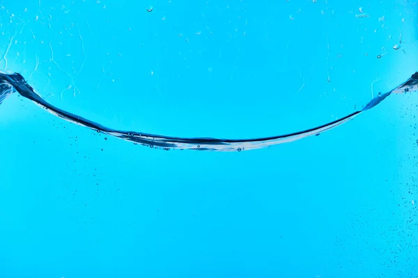 Água fresca transparente ondulada no fundo azul com gotas — Fotografia de Stock