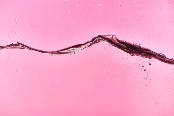 Wavy clear fresh water on pink background with drops and bubbles — Stock Photo