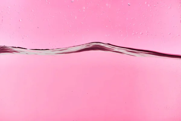 Wavy clear fresh water on pink background with drops — Stock Photo