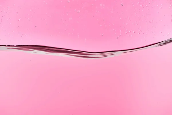 Wavy fresh water on pink background with drops — Stock Photo