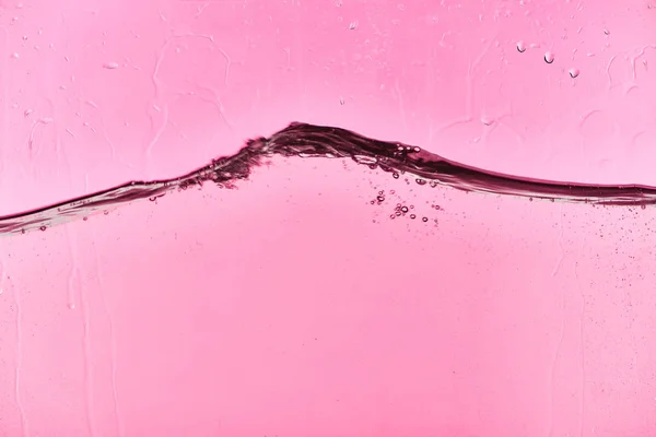 Acqua chiara ondulata su sfondo rosa con gocce — Foto stock