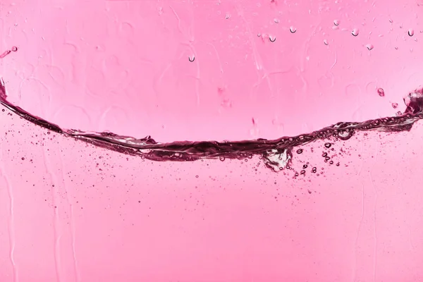 Agua dulce clara ondulada sobre fondo rosa con gotas de fugas - foto de stock