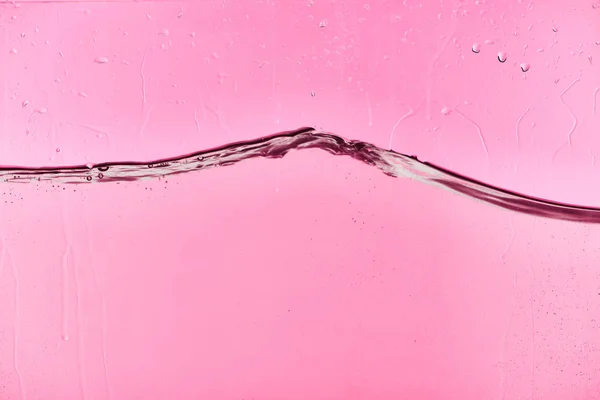 Wavy clear fresh water on pink background with flowing drops — Stock Photo