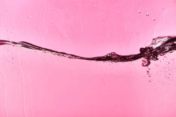 Klares Süßwasser auf rosa Hintergrund mit Tropfen — Stockfoto