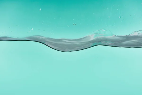 Eau transparente ondulée sur fond turquoise avec des gouttes qui fuient — Photo de stock