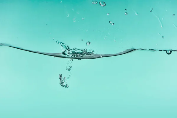Eau transparente ondulée sur fond turquoise avec éclaboussures et bulles — Photo de stock