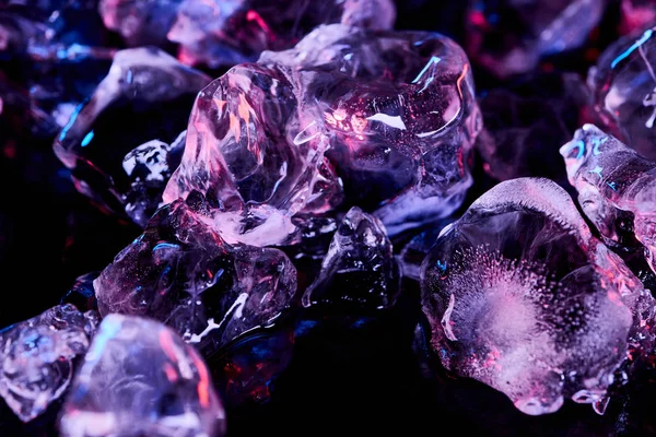 Frozen ice cubes with purple lighting isolated on black — Stock Photo