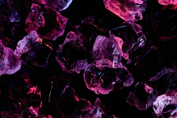 Vue de dessus des glaçons transparents avec éclairage violet isolé sur noir — Photo de stock