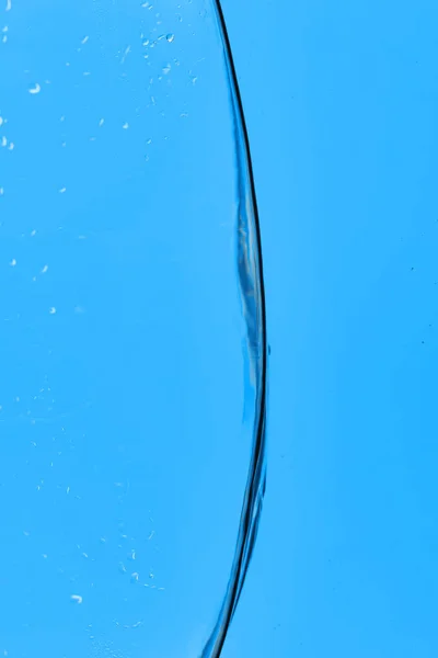 Eau transparente ondulée sur fond bleu avec des gouttelettes — Photo de stock