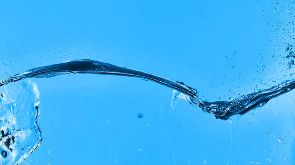 Água transparente ondulada no fundo azul com gotículas e respingo — Fotografia de Stock