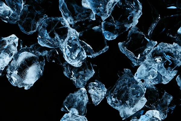 Vista superior de cubitos de hielo congelados con iluminación azul aislada en negro - foto de stock