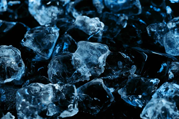 Cubitos congelados de hielo transparente con iluminación azul aislada en negro - foto de stock