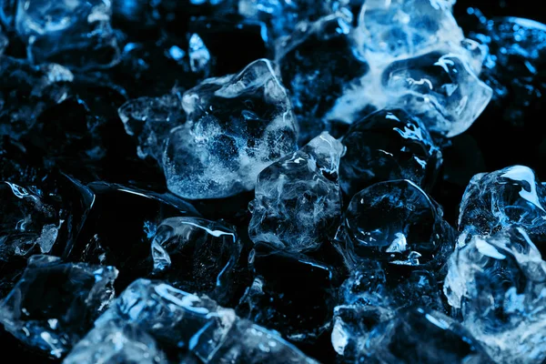 Frozen clear ice cubes with blue lighting isolated on black — Stock Photo