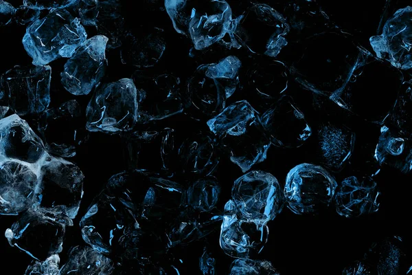 Vue de dessus des glaçons clairs gelés avec éclairage bleu isolé sur noir — Photo de stock