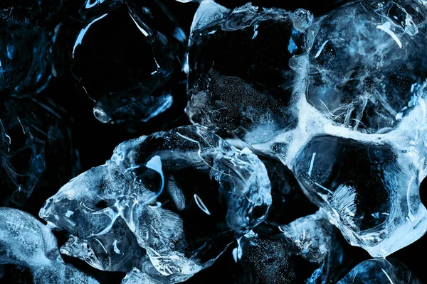 Cubos de gelo transparentes congelados com iluminação azul isolados a preto — Fotografia de Stock