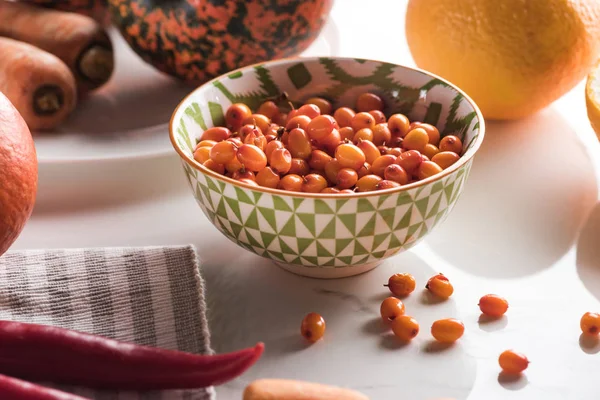 Bol avec de l'argousier entouré de légumes d'automne sur la surface du marbre — Photo de stock