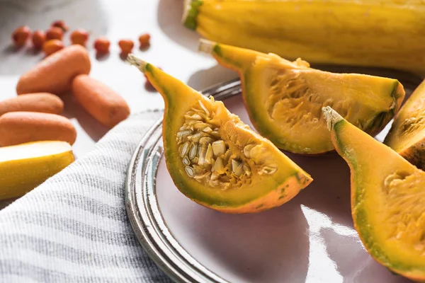 Plate with pumpkin quarters on striped towel — Stock Photo