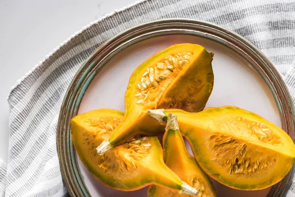 Top view of plate with pumpkin quarters on striped towel — Stock Photo