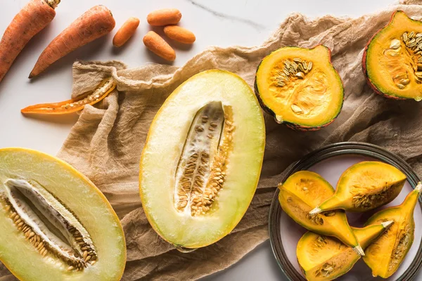 Vue de dessus des moitiés de melon, citrouille, carottes et courgettes sur toile — Photo de stock