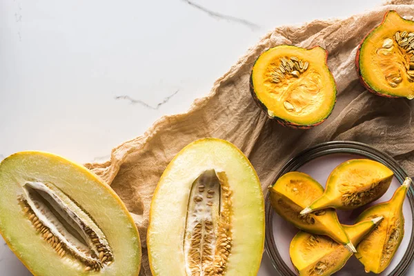 Vue de dessus des moitiés de melon et assiette avec citrouille sur toile — Photo de stock