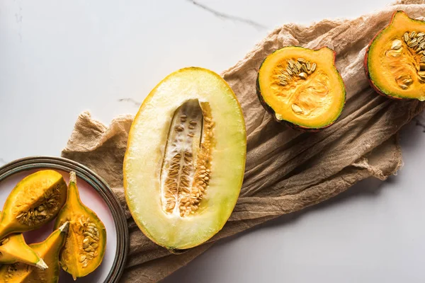 Vista superior de la mitad de melón y plato con calabaza sobre lienzo - foto de stock