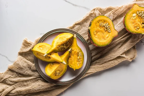 Top view of plate with pumpkin quarters and halves on canvas — Stock Photo