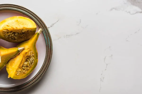 Top view of plate with pumpkin quarters on marble table — Stock Photo