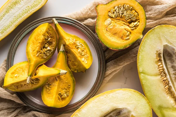 Teller mit Kürbisteilen und Melone auf Marmoroberfläche mit Leinwand — Stockfoto