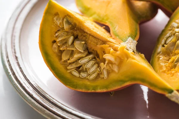 Plate with fresh ripe pumpkin quarters with seeds — Stock Photo