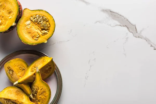 Top view of plate with ripe pumpkin pieces on marble surface — Stock Photo