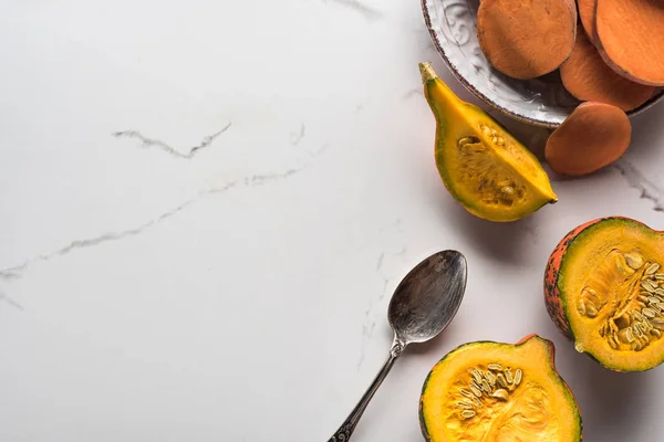 Top view of plate with sweet potato slices near pumpkin pieces on marble surface with spoon — Stock Photo