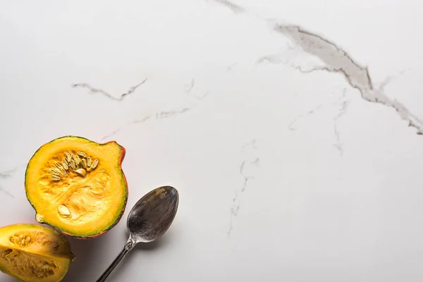 Vue de dessus de la moitié et du quart crus de citrouille sur la surface de marbre avec cuillère — Photo de stock