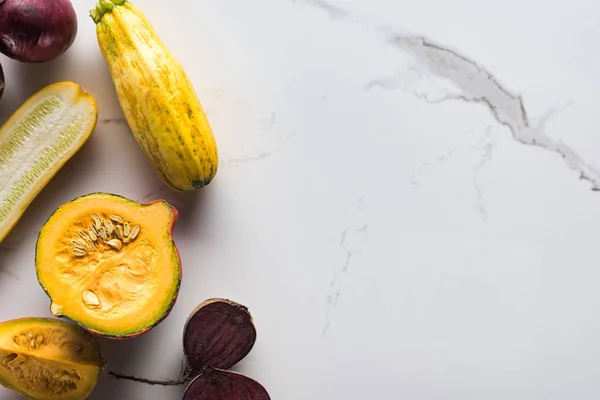 Vista superior de calabaza cruda, remolacha y trozos de calabacín en la superficie de mármol - foto de stock