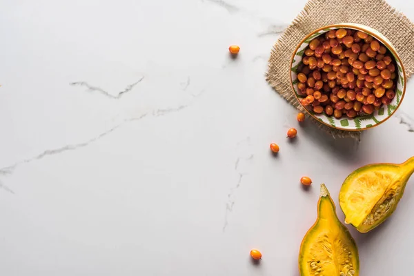 Draufsicht auf Schale mit Sanddorn in der Nähe von Kürbis auf Marmoroberfläche — Stockfoto