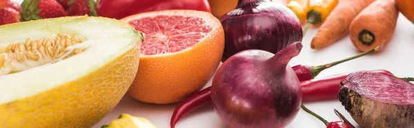 Plano panorámico de cebollas rojas, mitad pomelo, pimientos, melón y zanahorias sobre fondo blanco - foto de stock