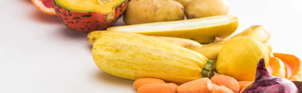 Plano panorámico de zanahorias, calabacín, limón y patatas sobre fondo blanco - foto de stock