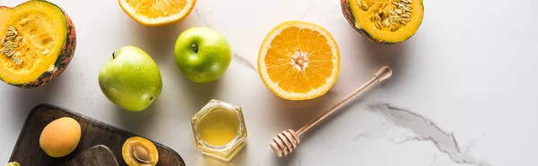 Colpo panoramico di taglieri con zucca, arancia, albicocche e miele sulla superficie di marmo — Foto stock