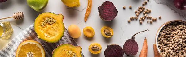 Панорамний знімок нуту біля сирих овочів і фруктів на мармуровій поверхні — стокове фото