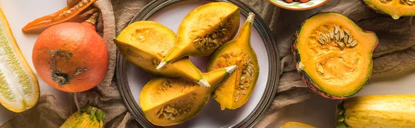 Panoramic shot of pumpkin and zucchini on plate on hessian — Stock Photo