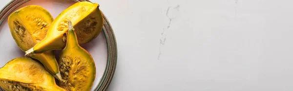 Панорамний знімок стиглого свіжого гарбуза на тарілці на мармуровому столі — стокове фото