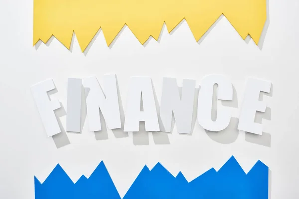 Top view of finance inscription with blue and yellow statistic graphs on white background — Stock Photo