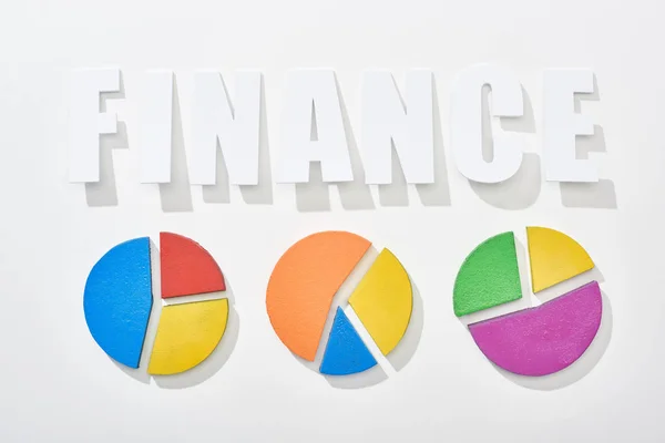 Vista superior da inscrição financeira perto de diagramas de torta multicolor no fundo branco — Fotografia de Stock