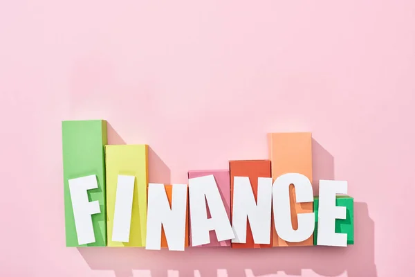 Vista superior de la inscripción de finanzas sobre el gráfico de bloques de color sobre fondo rosa - foto de stock
